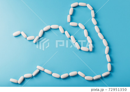 Biceps from white dragees with vitamins and minerals, Protein on a blue background. Biceps from white dragees with vitamins and minerals, Protein on a blue background. 72951350