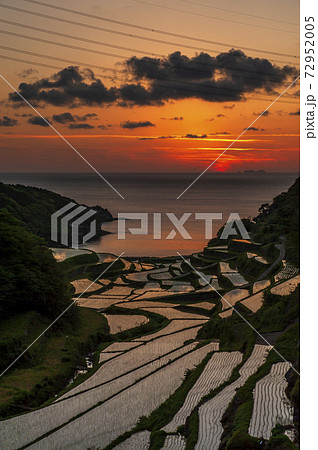 玄界灘の赤い夕日に照らされた佐賀県浜ノ浦棚田の写真素材