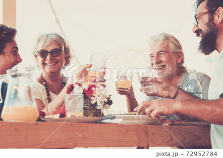 Happy group of people enjoy together toasting - mixed generations ages teenager adult mature have fun - caucasian family celebrate infriendship on a table with food and drinks Happy group of people enjoy together toasting - mixed generations ages teenager adult mature have fun - caucasian family celebrate infriendship on a table with food and drinks 72952784