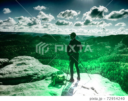 Man photographer with tripod are working on slope cliff. Man photographer with tripod are working on slope cliff. 72954240