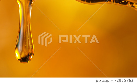 Pouring oil or honey drop on golden background. 72955762