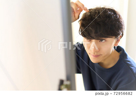 鏡を見ながら髪の毛を整える男性 72956682