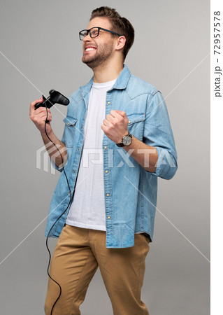 young man in casual jeans shirt holding joystick or gamepad playing game 72957578