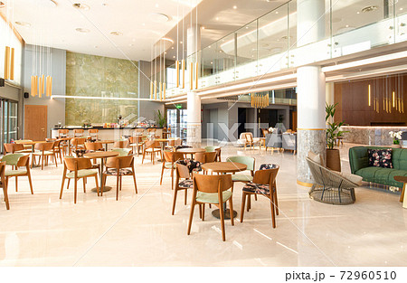 Light wooden and marble tile floor interior of modern cafe with double ceiling height. Lobby bar in luxury design hotel hall with second split level 72960510