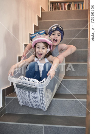 Kids sledding down stairs in a storage box Kids sledding down stairs in a storage box 72960556