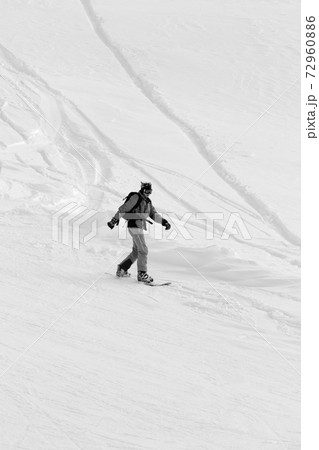 Snowboarder downhill on snowy off-piste slope after snowfall Snowboarder downhill on snowy off-piste slope after snowfall 72960886