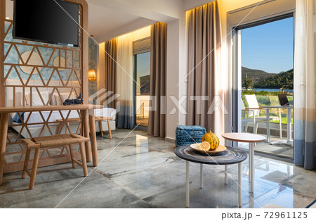 Modern interior of blue contemporary bedroom with handmade wicker wood furniture, handmade TV partition wooden wall,  summer landscape view in open French window terrace 72961125