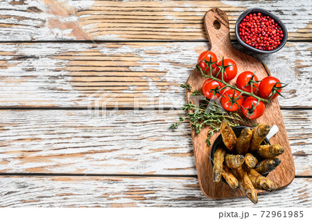 Whole fried capelin fish served on cutting board. White background. Top view. Copy space Whole fried capelin fish served on cutting board. White background. Top view. Copy space 72961985