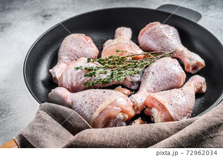 Raw organic chicken legs with spices and garlic ready to cook in a pan. White background. Top view 72962034