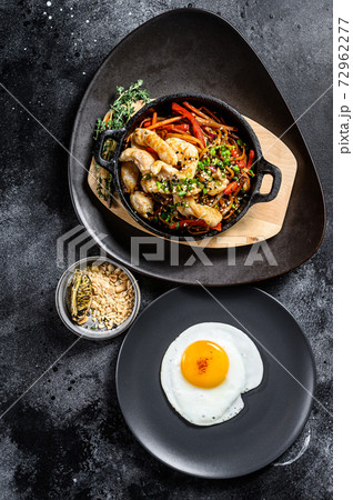 Udon stir fry noodles with chicken and vegetables in pan. Black background. Top view Udon stir fry noodles with chicken and vegetables in pan. Black background. Top view 72962277
