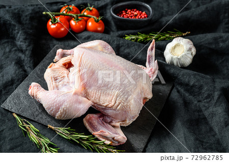Concept of cooking whole chicken with rosemary and pink pepper. Black background. Top view 72962785