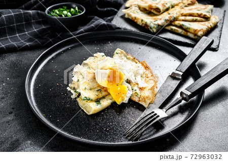 Plate of pancake stuffed with spinach and eggs. Black background. Top view Plate of pancake stuffed with spinach and eggs. Black background. Top view 72963032