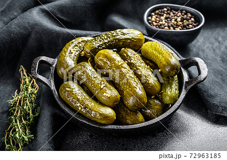 Marinated pickled cucumbers with herbs and spices. Black background. Top view Marinated pickled cucumbers with herbs and spices. Black background. Top view 72963185