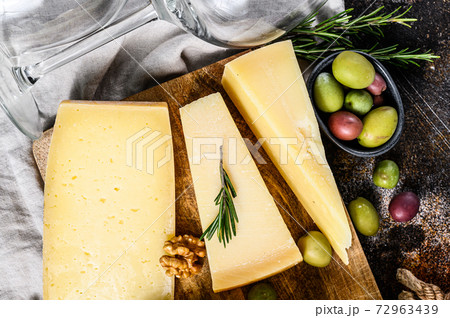 Collection of swiss, holland, french, italian cheeses with nuts and grapes. Dark background. Top view Collection of swiss, holland, french, italian cheeses with nuts and grapes. Dark background. Top view 72963439