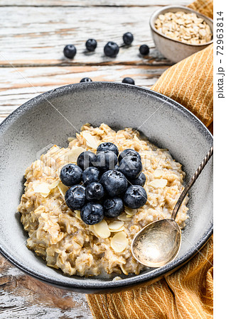 Breakfast oatmeal with blueberries and almonds. White wooden background. Top view 72963814