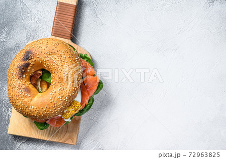 Bagel with salted salmon, cream cheese, avocado and egg. Gray background. Top view. Copy space 72963825