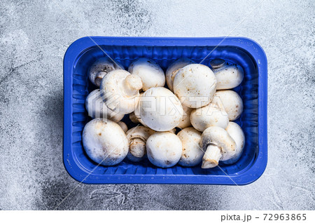 Fresh champignons in plastic packaging. Gray background. Top view Fresh champignons in plastic packaging. Gray background. Top view 72963865