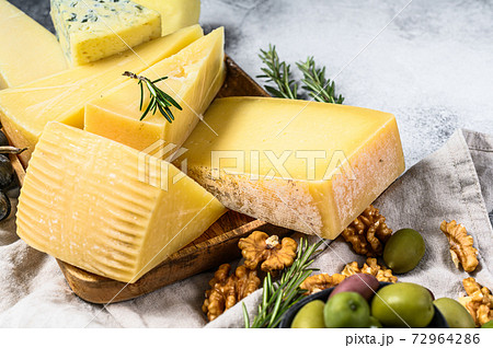 Different pieces of cheese with nuts olives and grapes. Assorted delicious snacks. Gray background. Top view 72964286