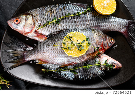 crucian carp with lemon and thyme on a black crucian carp with lemon and thyme on a black 72964621