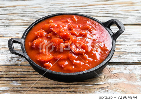 Chopped tinned red tomatoes in a pan. White 72964844