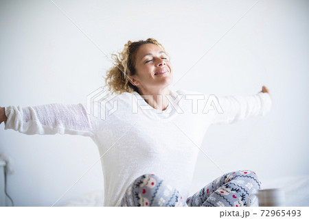 Happy beautiful woman wake up in the morning at home or hotel room enjoying the life with a smile and opening arms to stretch and start the new day - concept of waking up with joy Happy beautiful woman wake up in the morning at home or hotel room enjoying the life with a smile and opening arms to stretch and start the new day - concept of waking up with joy 72965493
