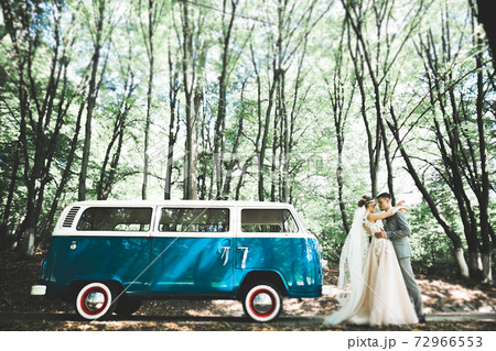 Beautiful newlywed couple posing near retro car Beautiful newlywed couple posing near retro car 72966553