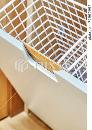 Modern wardrobe with opened metal mesh laundry basket. Wooden wardrobe with light gray cabinet doors. Close-up Modern wardrobe with opened metal mesh laundry basket. Wooden wardrobe with light gray cabinet doors. Close-up 72966997