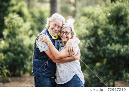 Beautiful elderly lifestyle senior couple hug and stay in love touching during outdoor leisure activity in the wood forest - green nature background and happy old people together Beautiful elderly lifestyle senior couple hug and stay in love touching during outdoor leisure activity in the wood forest - green nature background and happy old people together 72967259