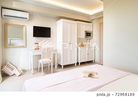 White elegant interior of small studio apartment room with classic style design wooden panel furniture in modern hotel flat. White elegant interior of small studio apartment room with classic style design wooden panel furniture in modern hotel flat. 72968189