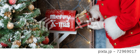 Close-up of hands of santa claus puts a gift in a mailbox. Christmas miracle 72969017