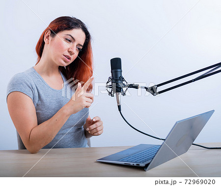 An emotional woman is broadcasting online on a laptop. Female radio presenter at the workplace 72969020