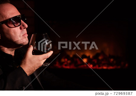 Mature man drinking cognac by the fireplace. Mature man drinking cognac by the fireplace. 72969387