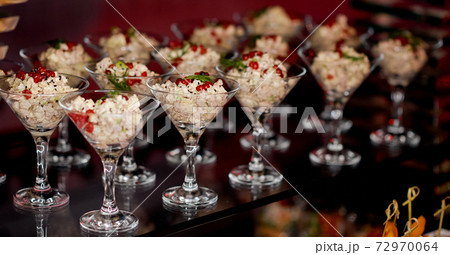 Waiter puts on a glass shelf salad with mayonnaise in glasses for Martini Waiter puts on a glass shelf salad with mayonnaise in glasses for Martini 72970064