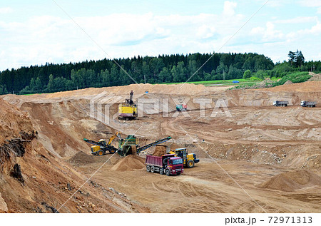 Wheel front-end loader loads sand into a dump truck. 72971313