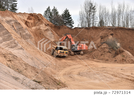 Excavator load the sand to the heavy mining truck in the open-pit. Heavy machinery Excavator load the sand to the heavy mining truck in the open-pit. Heavy machinery 72971314