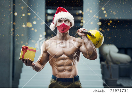 Fitness man in Santa Claus hat costume in gym Fitness man in Santa Claus hat costume in gym 72971754