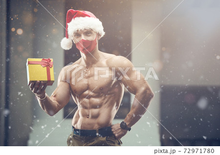 Fitness man in Santa Claus hat costume in gym 72971780