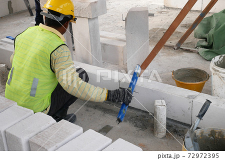SEREMBAN, MALAYSIA -MARCH 17, 2020: Blockwork by construction workers at the construction site. Workers laying the AAC brick and stacked it together using mortar to form the wall.  72972395