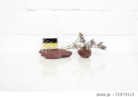 Cosmetic jar with yellow butter or cream with natural volcano stones and flower on white background 72973515