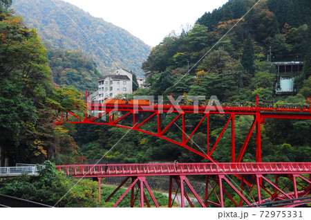 黒部峡谷入り口 宇奈月の赤い鉄橋と紅葉の写真素材