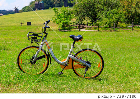 Modern bicycle parked on a green lawn in rural area 72977180