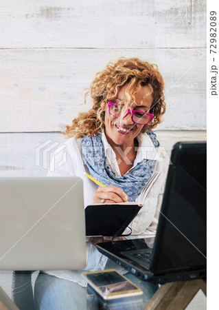 Happy cheerful people at work with technology computers in double laptop workstation - concept of business woman working on the desktop with technology - home economy for independent lady Happy cheerful people at work with technology computers in double laptop workstation - concept of business woman working on the desktop with technology - home economy for independent lady 72982089
