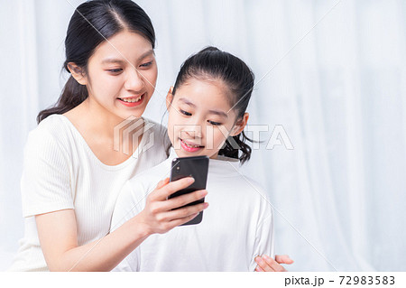 Mother and daughter using smartphone Mother and daughter using smartphone 72983583