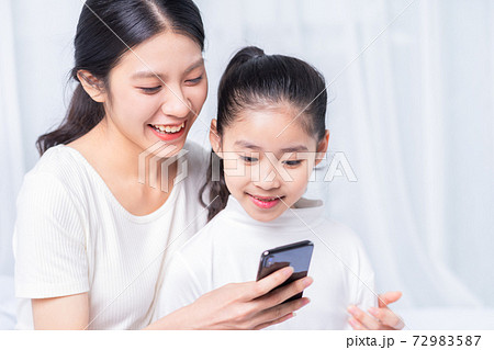 Mother and daughter using smartphone 72983587