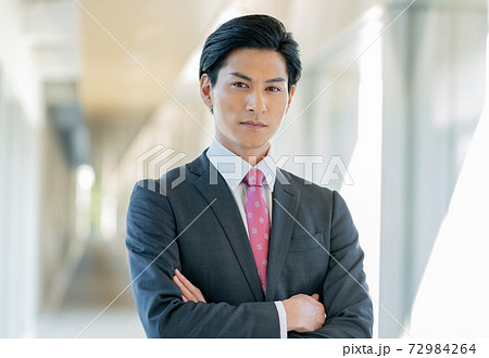 オフィスの廊下で腕組みをして立つ若い男性 72984264