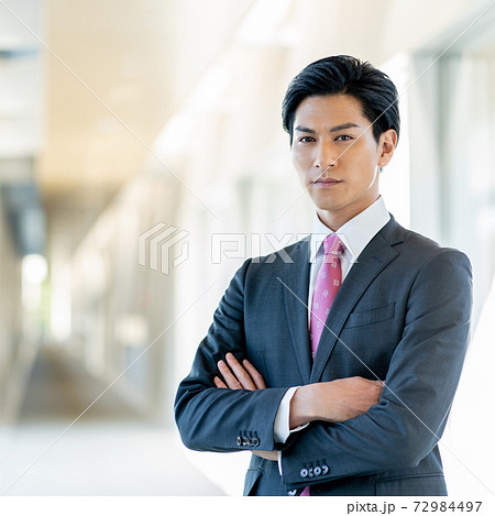 オフィスの廊下で腕組みをして立つ若い男性 正方形の写真素材