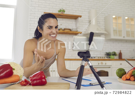 Cheerful fitness vlogger recording video about vegetarian diet and cooking healthy food 72984822