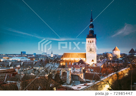 Tallinn, Estonia. Night Starry Sky Above Traditional Old Architecture Skyline In Old Town. St. Nicholas Church - Niguliste Kirik In Winter Evening Night. Famous Landmark. Altered Sky With Stars 72985447