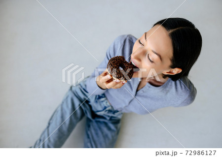 Portrait of rejoicing woman eats tasty donut at home. 72986127