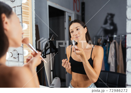 Reflection of young beautiful woman applying her make-up Reflection of young beautiful woman applying her make-up 72986272